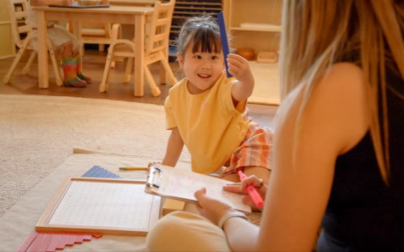 A San Tan Montessori preschool child sharing learning materials with a teacher