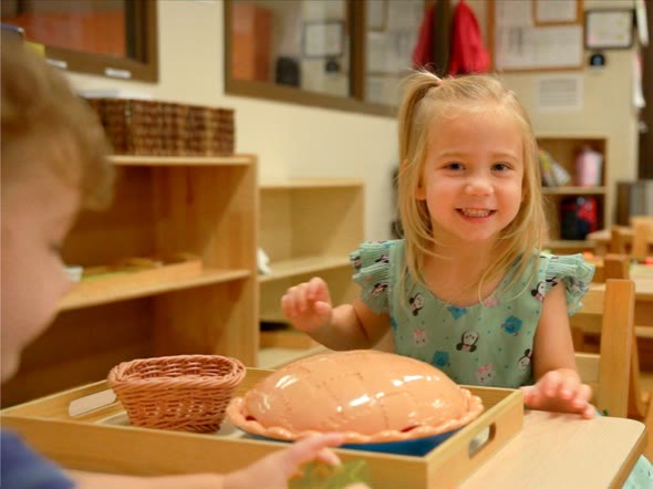A smiling San Tan Montessori preschool student exploring a hands-on classroom material