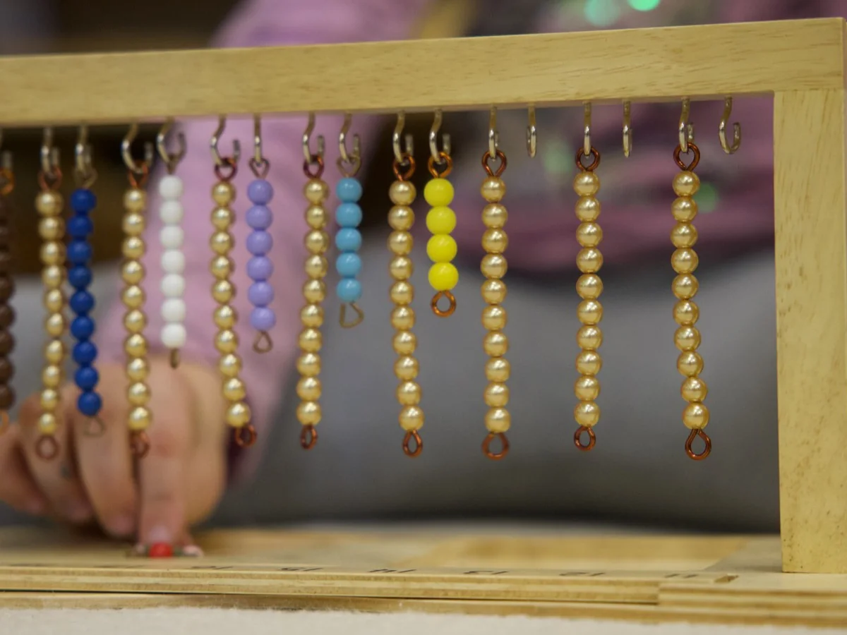 A child working with a hands-on Montessori bead material